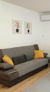 a gray couch in a living room with yellow pillows at Rose Apartmans in Jajce