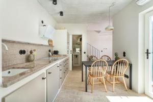 a kitchen with a black table and chairs at Casas da Formosa - Casa das Olarias in Tavira