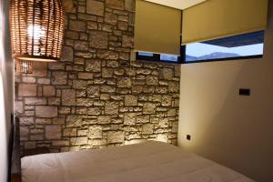 a bedroom with a stone wall and a bed at JN VILLA in Agios Ioannis Kaspaka