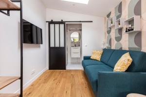 a living room with a blue couch and a tv at Studio à toutes proximités in Bry-sur-Marne
