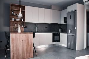 a kitchen with white cabinets and a stainless steel refrigerator at JN VILLA in Agios Ioannis Kaspaka