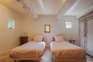 two beds in a room with white walls at L'Arbre d'Alice in Ongles