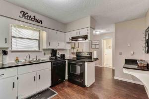 a kitchen with white cabinets and black appliances at Getaway at JAX in Jacksonville