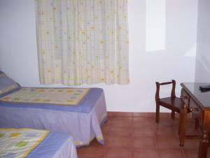 a room with two beds and a table and a window at Casa Concha in Almadén de la Plata