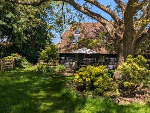 een huis met een boom in een tuin bij Cosy listed barn in peaceful country village in Grandborough