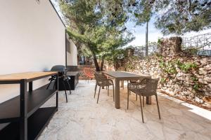 un patio con tavoli, sedie e un muro in pietra di Tiny home Rubi in Oaza Mira resort a Drage
