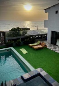 a house with a swimming pool and the ocean at La residence latinaya in Poponguine