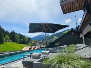un grande ombrellone nero seduto accanto alla piscina di ALMMONTE PRÄCLARUM SUITES Design Hotel a Wagrain