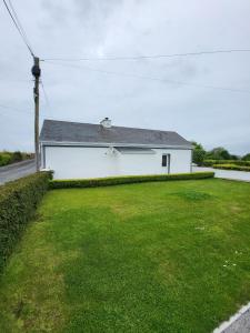 une maison blanche avec une pelouse verte devant elle dans l'établissement 3 bed Country cottage, à Swinford