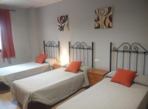 Habitación con 3 camas con almohadas de color naranja en Hostal la Molina, en Álora