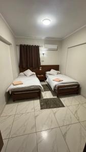 two beds in a room with a tiled floor at Royal hotel Tanta - فندق رويال طنطا in Tanta
