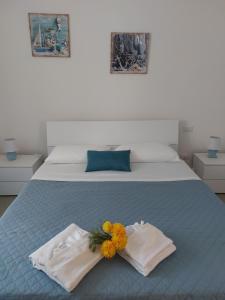a bedroom with two towels and flowers on a bed at Suite LA CONCHIGLIA località Caccia e Riserva in Santa Marinella