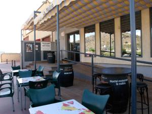 Un restaurante con mesas y sillas frente a un edificio. en Hostal la Molina, en Álora