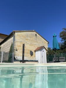 um edifício ao lado de uma piscina com um guarda-sol em Cinégîte du jardin aux étoiles - Proche de Saint Emilion em Saint-Pey-de-Castets