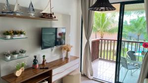 ein Wohnzimmer mit einem TV und einem Balkon in der Unterkunft Muro Alto -Flat - Porto de Galinhas Beira mar in Porto De Galinhas