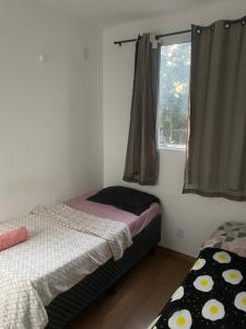 a small bedroom with two beds and a window at Milenium residence 206 in Juiz de Fora