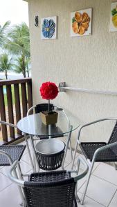 ein Glastisch und Stühle mit einer roten Blume darauf in der Unterkunft Muro Alto -Flat - Porto de Galinhas Beira mar in Porto De Galinhas + 11 Fotos