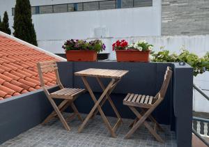 桑塔納的住宿－Vivenda Ferreira，阳台上摆放着两把椅子和一张桌子,阳台上摆放着鲜花