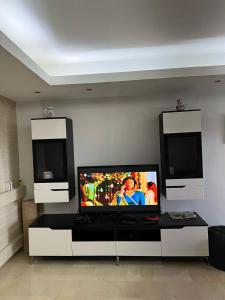 un salon avec une télévision à écran plat sur une table dans l'établissement Plage des nations, à Sale