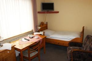 Zimmer mit einem Bett und einem Schreibtisch mit einem Tisch in der Unterkunft Döhling's Gasthaus in Morsum