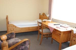 um quarto com uma secretária, uma cama, uma mesa e cadeiras em Döhling's Gasthaus em Morsum