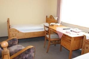 a room with a desk and a bed and a table and chairs at Döhling's Gasthaus in Morsum