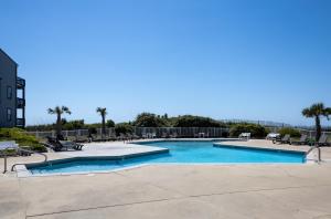 a large swimming pool with chairs and a building at Oceanfront Pool Balcony at Ospreys Nest in North Topsail Beach in North Topsail Beach