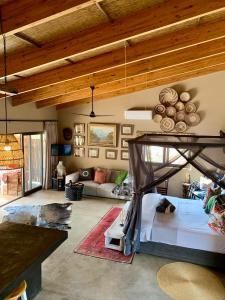 a bedroom with a bed and a living room at Rooibos Luxury Bush Cottage in Hoedspruit