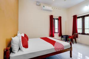 um quarto com uma cama com almofadas vermelhas e brancas em OYO Flagship SIVANANDA HOMESTAY em Varkala