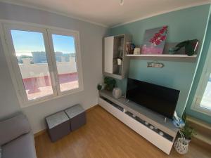 a living room with a flat screen tv and two windows at Coqueto ático con vistas al mar y a la montaña Auto Check-in in Miami Platja +21 photos