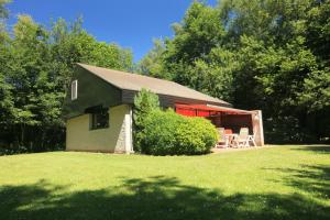 a black house with a red roof and chairs in a yard at Bungalow het Zuiderveld in Geesbrug +5 photos