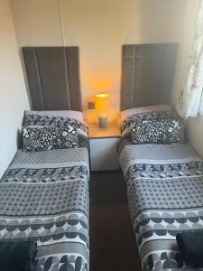 2 camas en una habitación con una mesa y una lámpara en Beautiful caravan on Billing Aquadrome, en Northampton