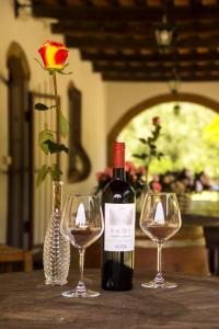 eine Flasche Wein und zwei Weingläser auf dem Tisch in der Unterkunft Villa Cresci con piscina in Sassetta