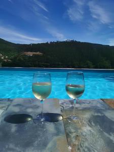 dos vasos de vino sentados en una mesa junto al agua en Quinta Torres de Azevedo by North Star Flats, en Sebolido