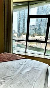 a bedroom with a view of a city from a window at Wonderful two bed room with full marina view in Dubai