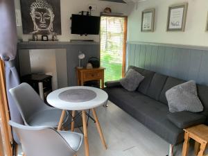 a living room with a couch and a table at Hedgehog Lodge in Colwall