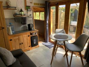 uma sala de estar com uma mesa e uma cozinha em Hedgehog Lodge em Colwall