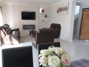 a living room with leather furniture and a bouquet of flowers at LND GUEST HOUSE in Bloubergstrand