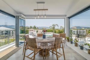 a dining room with a table and chairs and large windows at Villa Shangri-La Zakinthos in Zakynthos Town