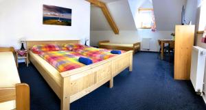 um quarto com uma cama de madeira e um edredão colorido em Penzion Eliška em Petříkov