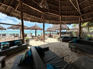 una sala de estar con sofás y sombrillas en la playa en Bahari Beach Bungalows en Jambiani