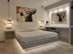 Aphrodite Hotel & Apartments في إيوس خورا: غرفة نوم بسرير ودهان على الحائط