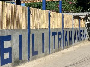 a fence with blue writing on the side of it at Hostel Gili Trawangan in Gili Trawangan