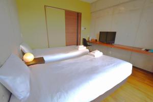 a room with two beds and a television at Hotel Pescatore Okinawa in Naha
