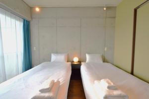 2 camas en una habitación pequeña con ventana en Hotel Pescatore Okinawa en Naha
