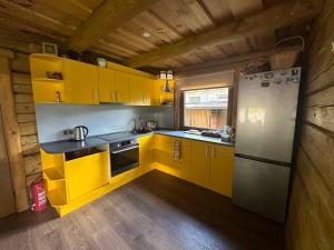 uma cozinha com armários amarelos e um frigorífico em Guļbūve ar saunu, kamīnu em Saulkrasti