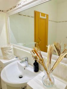 ライプツィヒにあるKunstviertel Apartment am Kanalの洗面台と枯れ草が入った花瓶のあるバスルーム +10枚の写真