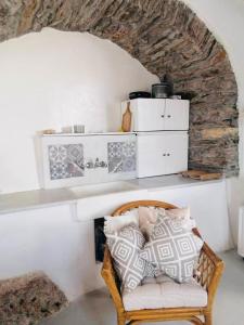 a wicker chair in a room with a stone wall at Naxos Mountain Retreat - Tiny House Build on Rock in Kóronos