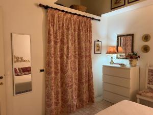 een slaapkamer met een gordijn, een dressoir en een spiegel bij Casa Mariuccia in Carloforte