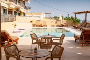 uma piscina com mesas e cadeiras ao lado de um pátio em Maria Resort Parga em Parga